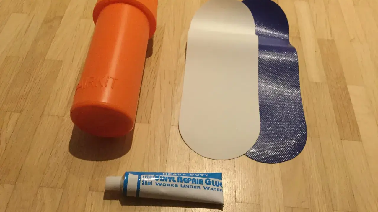 Reparaturset für Schlauchboote: Kleber, Flicken und eine orangefarbene Aufbewahrungsdose.