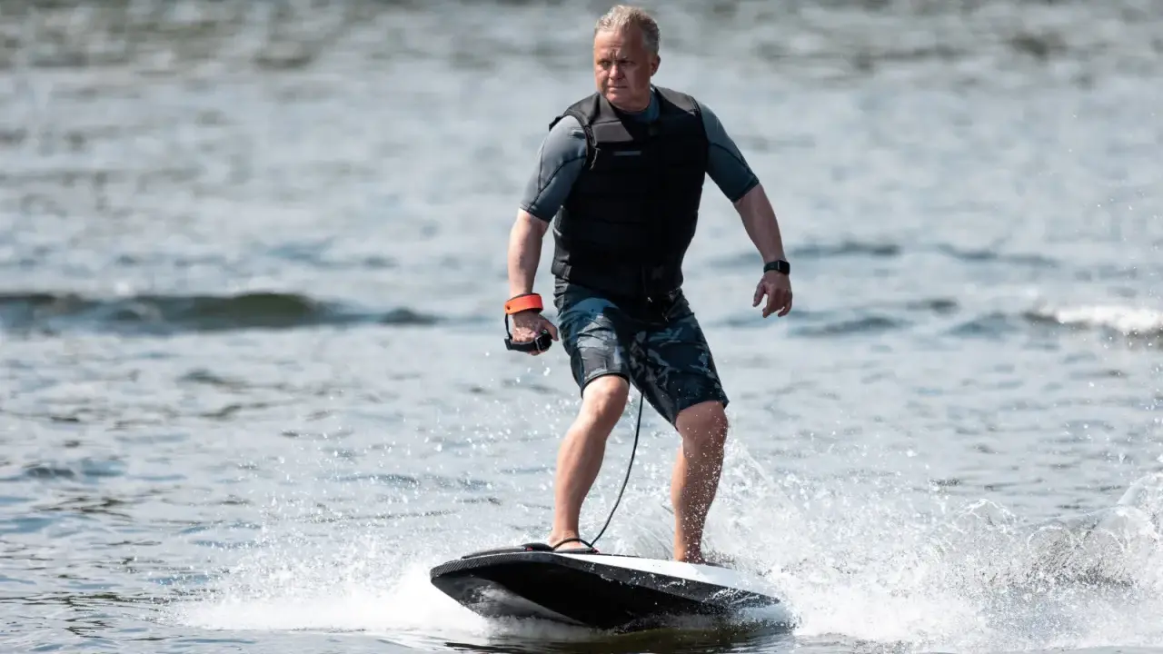 Mann fährt mit einem Surfbrett mit Motor über das Wasser.