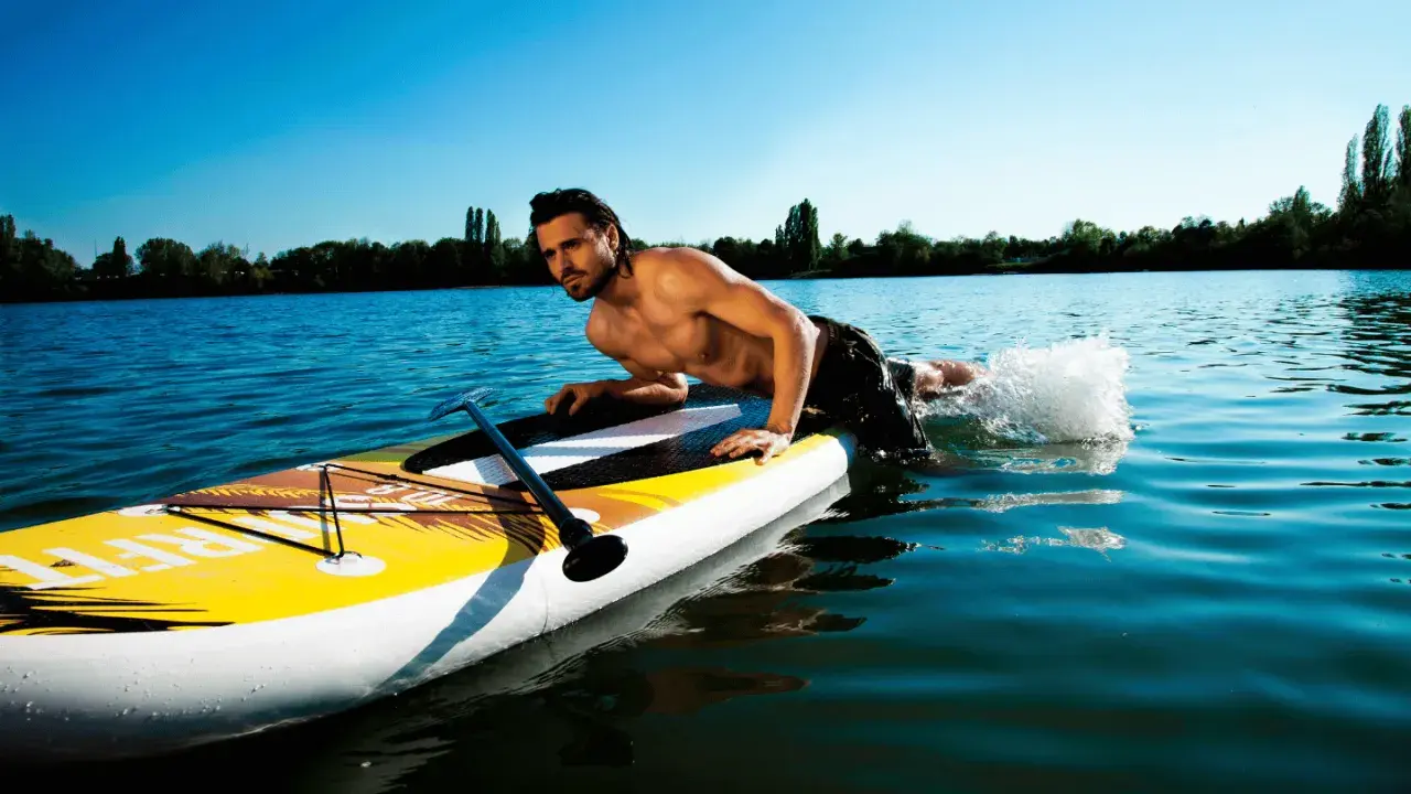 Mann liegt auf SUP-Board, paddelt mit Armen im Wasser. Perfekt für eine SUP Tour auf dem See.