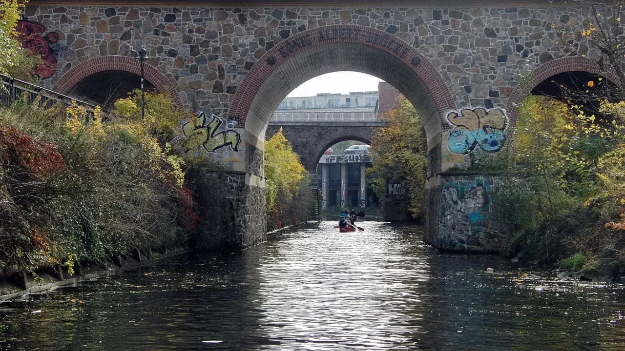 Kanus auf dem Fluss unter einer Steinbrücke mit Graffiti. Sup Leipzig!