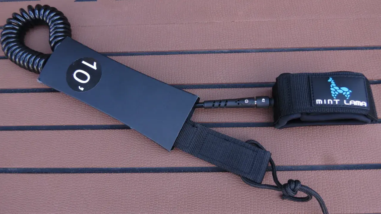 Schwarze SUP Leash mit 10' Kennzeichnung und Mint Lama Logo, bereit zur Befestigung.