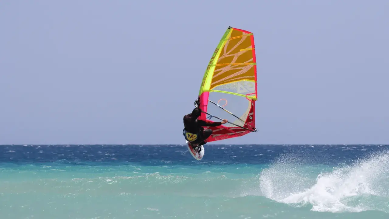 Windsurfer springt hoch über türkisfarbener Welle vor Teneriffa. Ein spektakulärer Sprung beim Teneriffa Windsurfen.