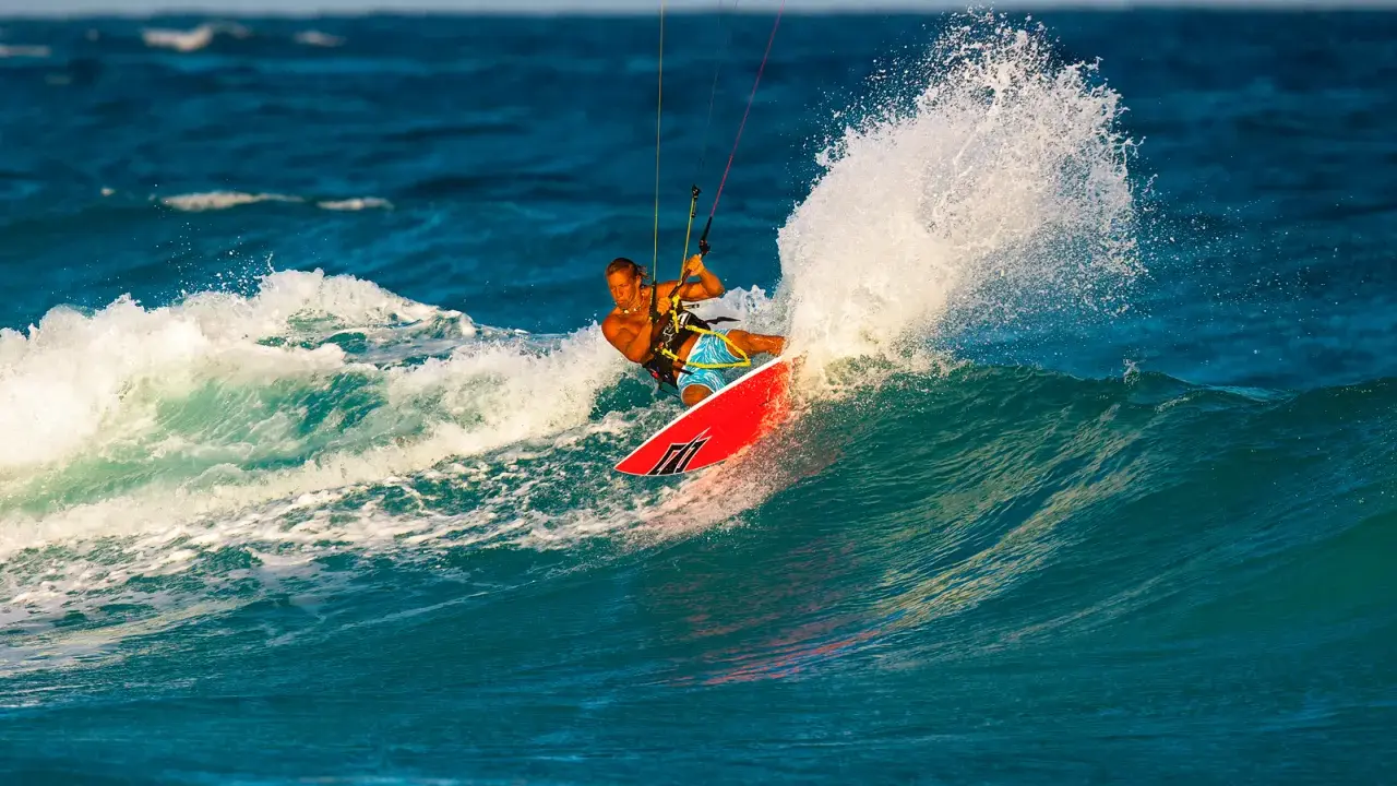 Brian Talma surft auf einer Welle, während er mit einem Kiteboard durch die Gischt fährt.