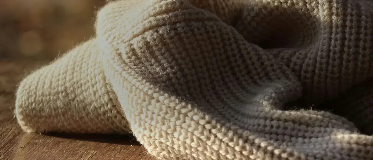 Weiches, cremefarbenes Strickgewebe, das an die Herkunft von Merinowolle erinnert.