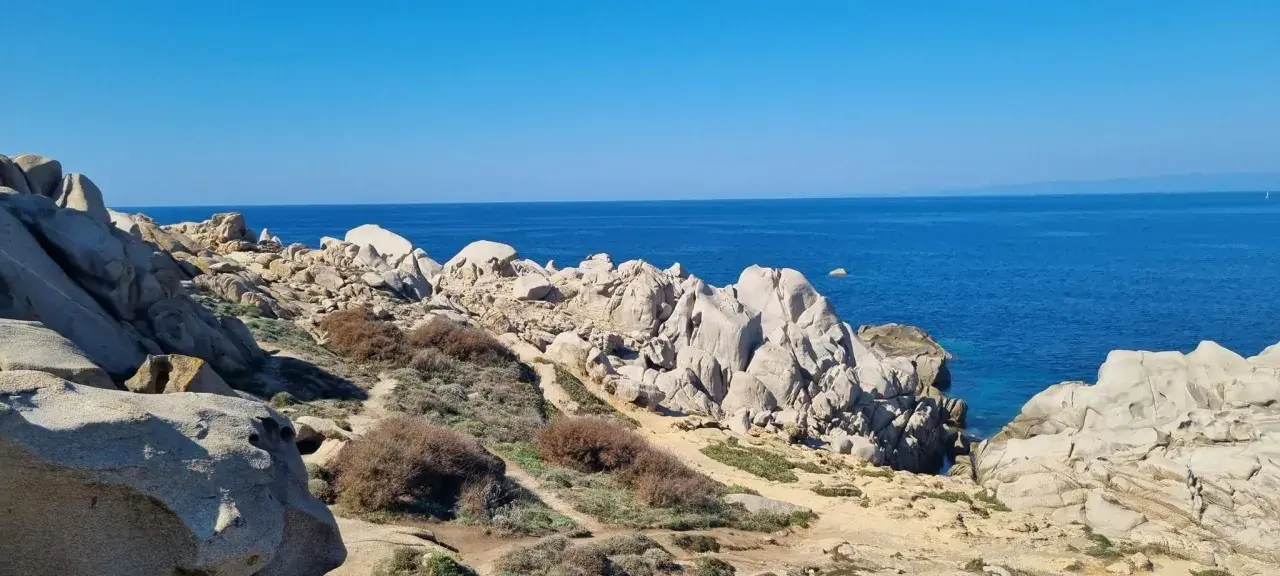 Felsige Küste am Capo Testa, Sardinien, mit tiefblauem Meer und klarem Himmel.