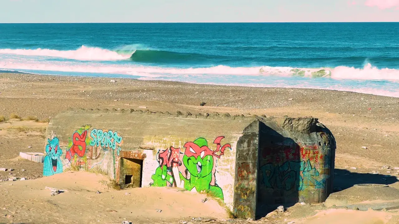 Bunker mit Graffiti am Strand von Klitmoller, Dänemark. Wellen brechen im Meer.