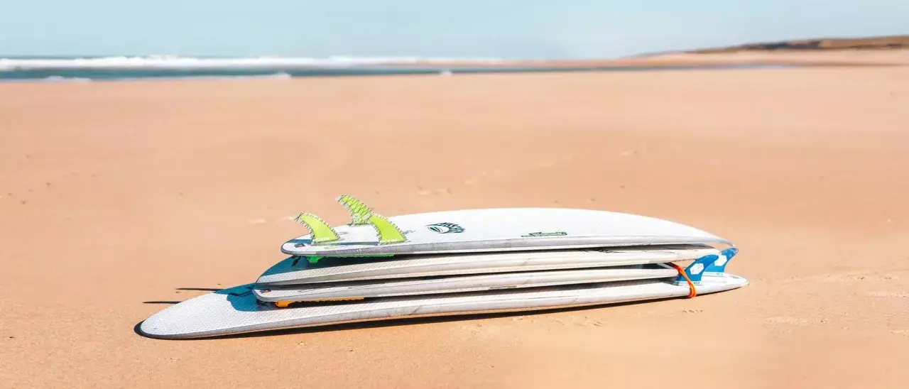Gestapelte Surfbretter am Strand, verschiedene surfbrett größe für unterschiedliche Wellen.