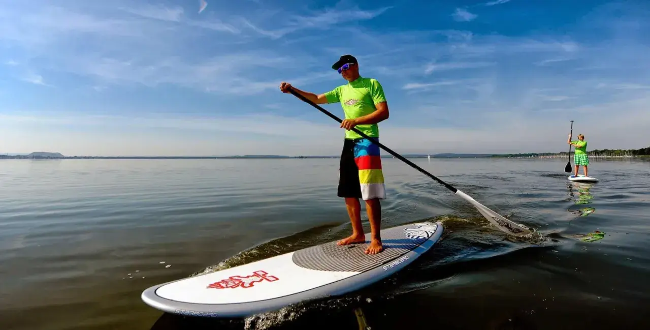 Ein Mann genießt das Steinhuder Meer beim SUP. Im Hintergrund paddelt eine weitere Person.