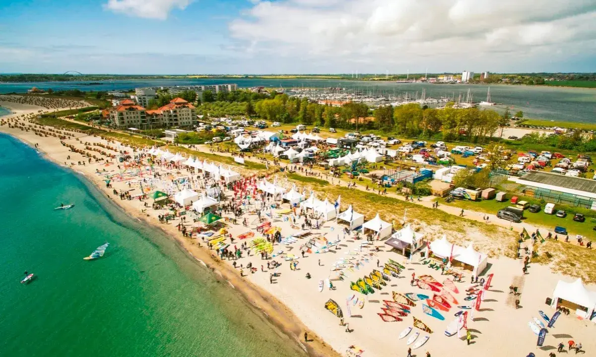 Strandfest mit vielen Zelten und Ausrüstung für Windsurfing Wulfen. Menschen genießen das sonnige Wetter am Meer.