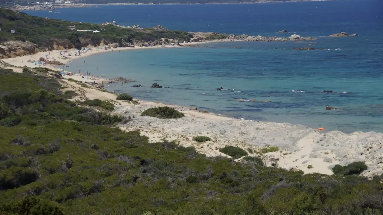 Ein sonniger Tag am Vignola Mare. Türkisfarbenes Meer, Sandstrand mit wenigen Menschen und üppige grüne Vegetation.