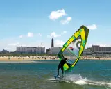 Windsurfer auf dem Meer vor Borkum, im Hintergrund der Strand mit Menschen und Hotels.
