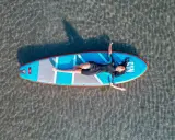 Frauen entspannt auf einem SUP-Board in NRW liegend. Das Board ist blau mit roten Akzenten.