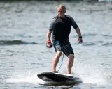 Mann fährt mit einem Surfbrett mit Motor über das Wasser.