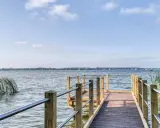 Holzsteg am Zwischenahner Meer mit Segelbooten am Horizont und Schilf am Ufer.