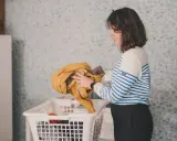 Frau sortiert gelbe Jacke und andere Kleidung für die sportsachen waschen.