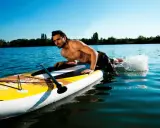 Mann liegt auf SUP-Board, paddelt mit Armen im Wasser. Perfekt für eine SUP Tour auf dem See.