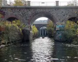 Kanus auf dem Fluss unter einer Steinbrücke mit Graffiti. Sup Leipzig!