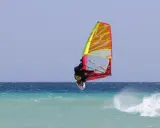 Windsurfer springt hoch über türkisfarbener Welle vor Teneriffa. Ein spektakulärer Sprung beim Teneriffa Windsurfen.