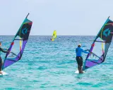 Windsurfer auf dem Meer vor Santa Maria Sal. Zwei Surfer mit bunten Segeln genießen den Tag auf dem türkisfarbenen Wasser.