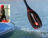 Mann bereitet sich auf ein sup fest vor. Ein Paddel mit schwarzem Carbonmuster und roten Akzenten taucht ins Wasser.
