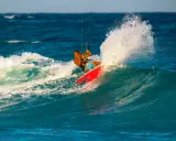 Brian Talma surft auf einer Welle, während er mit einem Kiteboard durch die Gischt fährt.