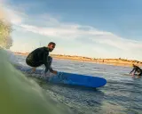 Surfer reitet eine Welle vor der Küste von Tarifa. Ein weiterer Surfer wartet im Wasser.