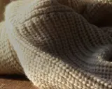Weiches, cremefarbenes Strickgewebe, das an die Herkunft von Merinowolle erinnert.