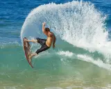 Mann surft ohne segel auf einer welle, die Gischt spritzt. Ein aufregender Moment des Wassersports.