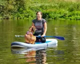Frau und ihr sup hund krallen auf dem Fluss.