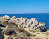 Felsige Küste am Capo Testa, Sardinien, mit tiefblauem Meer und klarem Himmel.