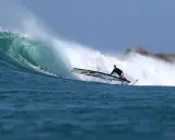 Liam Dunkerbeck surft eine massive Welle, die Gischt spritzt.