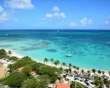 Traumhafter Strand mit Palmen und türkisfarbenem Wasser. Ein Ort wie Aruba oder Curacao, perfekt für einen Urlaub.