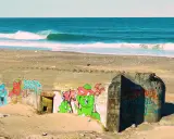 Bunker mit Graffiti am Strand von Klitmoller, Dänemark. Wellen brechen im Meer.