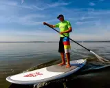 Ein Mann genießt das Steinhuder Meer beim SUP. Im Hintergrund paddelt eine weitere Person.
