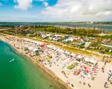 Strandfest mit vielen Zelten und Ausrüstung für Windsurfing Wulfen. Menschen genießen das sonnige Wetter am Meer.