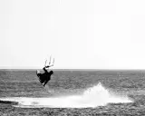 Kitesurfer in der Luft vor Fehmarn. Ein Sprung über das Wasser, der die Freiheit des Windsurfens zeigt.