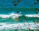 Windsurfer auf einer Welle vor Bornholm. Das türkisfarbene Meer und die Gischt erzeugen ein dynamisches Bild vom Surfen.