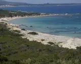 Ein sonniger Tag am Vignola Mare. Türkisfarbenes Meer, Sandstrand mit wenigen Menschen und üppige grüne Vegetation.