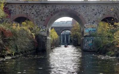 Kanus auf dem Fluss unter einer Steinbrücke mit Graffiti. Sup Leipzig!