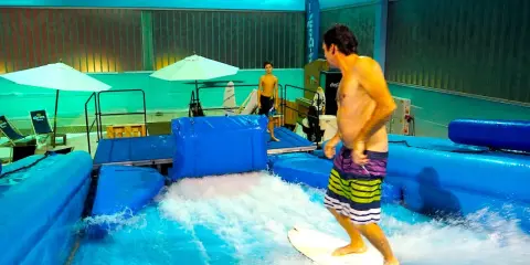 Mann surft auf einer künstlichen hamburger Welle. Ein Junge beobachtet ihn.