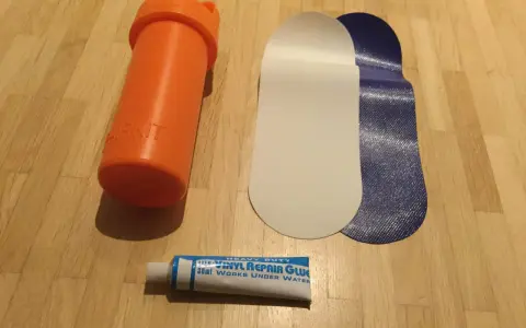 Reparaturset für Schlauchboote: Kleber, Flicken und eine orangefarbene Aufbewahrungsdose.