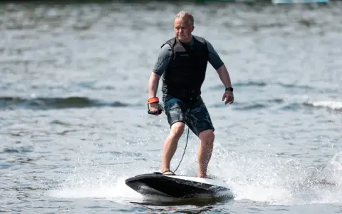 Mann fährt mit einem Surfbrett mit Motor über das Wasser.
