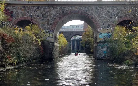 Kanus auf dem Fluss unter einer Steinbrücke mit Graffiti. Sup Leipzig!