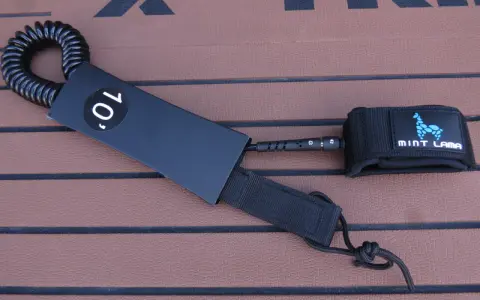 Schwarze SUP Leash mit 10' Kennzeichnung und Mint Lama Logo, bereit zur Befestigung.