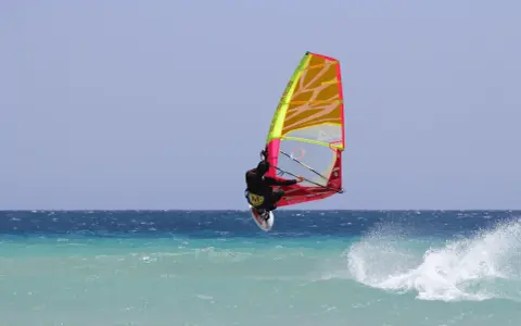 Windsurfer springt hoch über türkisfarbener Welle vor Teneriffa. Ein spektakulärer Sprung beim Teneriffa Windsurfen.