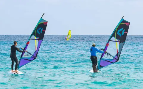 Windsurfer auf dem Meer vor Santa Maria Sal. Zwei Surfer mit bunten Segeln genießen den Tag auf dem türkisfarbenen Wasser.