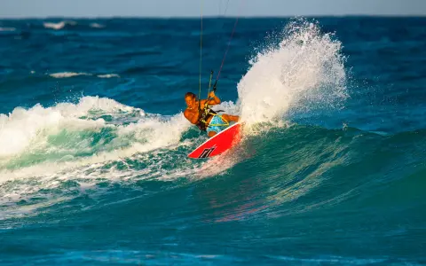 Brian Talma surft auf einer Welle, während er mit einem Kiteboard durch die Gischt fährt.