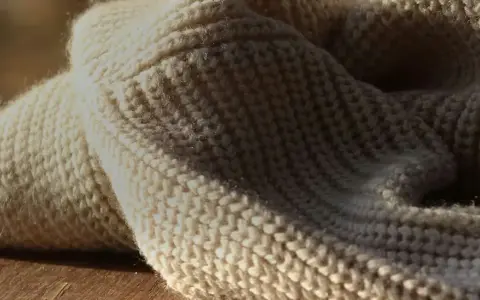 Weiches, cremefarbenes Strickgewebe, das an die Herkunft von Merinowolle erinnert.
