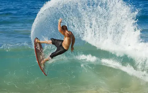 Mann surft ohne segel auf einer welle, die Gischt spritzt. Ein aufregender Moment des Wassersports.