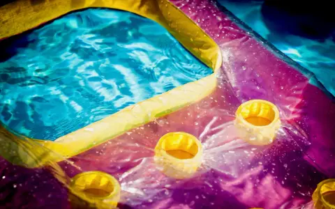 Bunte Luftmatratze mit Becherhaltern im Wasser, bereit zum Luftmatratze flicken.